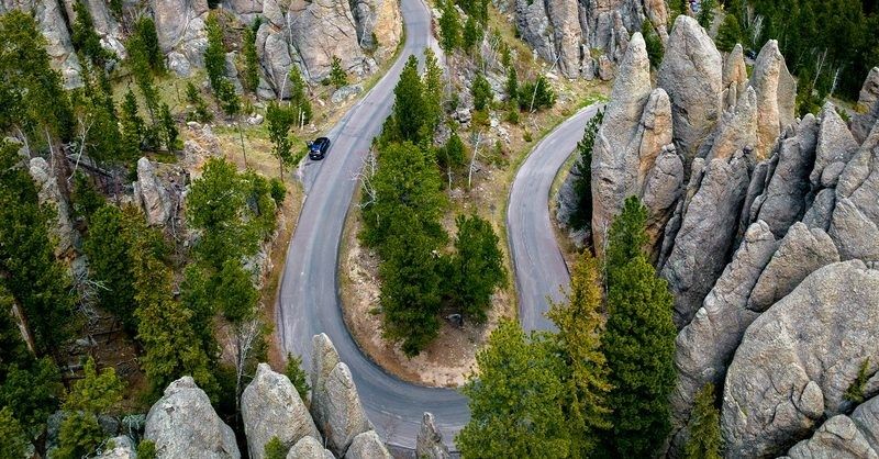 Winding paved road through forested, rocky mountain formations